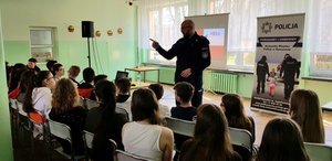 Policjant w sali lekcyjnej prowadzi zajęcia dla uczniów Szkoły Podstawowej nr 16 w Rzeszowie.