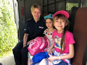 Policjantka wraz z dwoma dziewczynkami siedzi w radiowozie policyjnym.