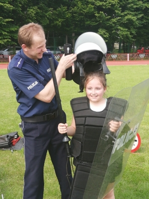 Policjant ubiera dziewczynkę w kamizelkę taktyczną i hełm