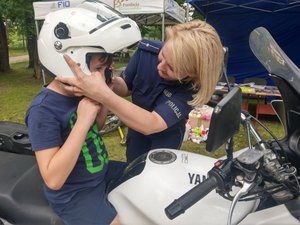 policjantka zakłada kask dziecku na motocyklu
