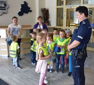 Fotografia kolorowa. Na zdjęciu, w holu budynku KPP Jarosław widać dziewczynę wręczającą policjantce laurkę. W tle znajdują się dzieci oraz opiekunowie.