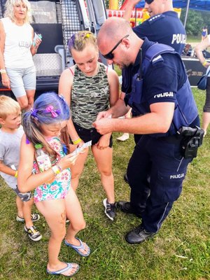 Policjant rozdaje ulotki dzieciom