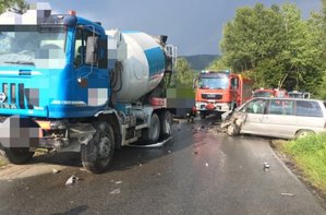 zdjęcie z miejsca kolizji drogowej w Ustjanowej. Widoczna uszkodzona ciężarówka i samochód osobowy peugeot, a w tle pojazdy służb ratowniczych.