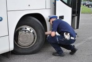 Fotografia przedstawia policjanta ruchu drogowego dokonującego kontroli autobusu.