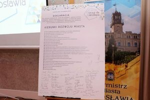 Na zdjęciu widać tablicę na której widnieje deklaracja. Na deklaracji znajdują się tematy związane z kierunkami rozwoju miasta oraz podpisy uczestników konferencji.