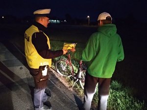 policjant daje rowerzyście kamizelkę odblaskową