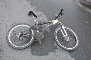 Uszkodzony rower, który leży na jezdni.
