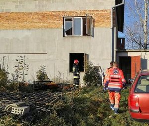 Miejsce pożaru budynku w Hawłowicach. Przy oknie budynku stoi strażak. Widoczny jest także ratownik medyczny.