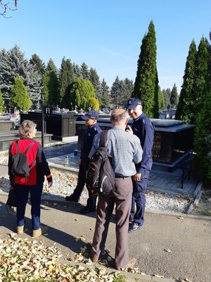 Policjanci rozmawiają z osobami, które odwiedzają groby.