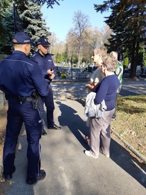 Policjanci rozmawiają z osobami, które odwiedzają groby.