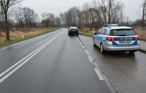 Miejsce wypadku drogowego w Pruchniku. Po prawej stronie zdjęcia znajduje się radiowóz a w tle samochód osobowy.