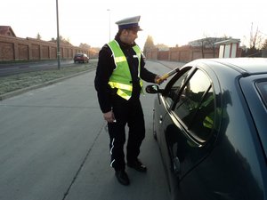 policjant wydziału ruchu drogowego podczas badania urządzeniem na zawartość alkoholu w czasie kontroli drogowej
