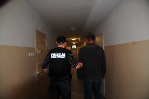 zdjęcie poglądowe, pochodzące z archiwum KPP Mielec, policjant prowadzący mężczyznę do celi