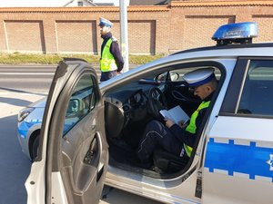 policjant podczas kontroli drogowej, na fotografii w radiowozie sporządza dokumentacje