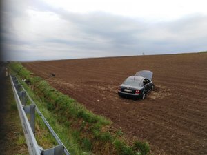 Na przydrożnym polu stoi uszkodzony samochód marki Volkswagen
