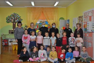 Zdjęcie kolorowe przedstawia całą grupę przedszkolną wraz z dwoma wychowawcami, dyrektorka przedszkolną oraz trzy policjantki . Dzieci ubrane kolorowo .