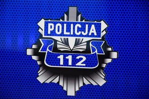 Policyjna odznaka z napisem Policja i numerem alarmowym 112