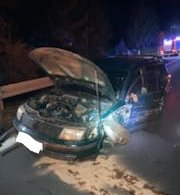 Zdjęcie zrobione w porze nocnej. Na pierwszym planie rozbity samochód, który uczestniczył w kolizji, a w tle pojazdy ratunkowe.