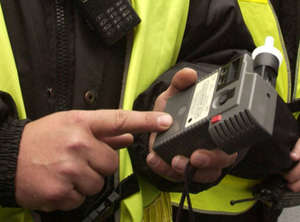 Zdjęcie przedstawia zbliżenie na dłonie policjanta ruchu drogowego, który trzyma urządzenie do pomiaru trzeźwości.