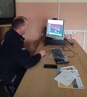 Policjant siedzący przed monitorem komputera. Na monitorze wyświetlający się slajd prezentacji.
