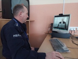 Na zdjęciu policjant siedzący przed monitorem komputerowym podczas zajęć online.