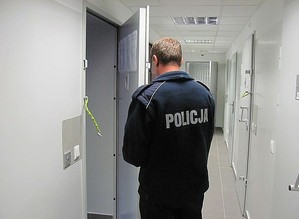 Policjant zamykający pomieszczenie dla osób zatrzymanych