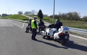 kontrola drogowa, na poboczu drogi trzy motocykle, na nich kierowcy, po lewej stronie policjant