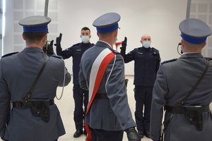 Nowo przyjęci policjanci podczas ślubowania w auli Oddziału Prewencji Policji w Rzeszowie, stoją frontem do pocztu sztandarowego.