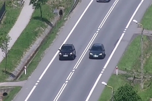 Zdjęcie z policyjnego drona. Dwa samochody jadące prostym odcinkiem drogi. Jeden z pojazdów wyprzedza drugi w miejscu niedozwolonym (podwójna linia ciągła).