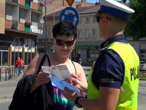 policjant ruchu drogowego przekazuje ulotkę kobiecie w rejonie przejścia dla pieszych