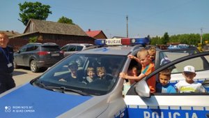 Na zdjęciu znajduje się radiowóz policyjny i kilkoro dzieci wewnątrz pojazdu