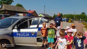 Na zdjęciu znajduje się policjant i radiowóz wraz                z dziećmi