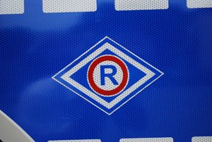 Duża litera R na radiowozie policyjnym, oznaczenia służby ruchu drogowego.