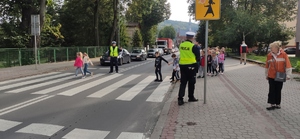 dzieci przechodzą przez przejście dla pieszych, policjant kieruje ruchem