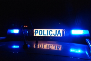 Zdjęcie przedstawia belkę z napisem policja i niebieskimi światłami.