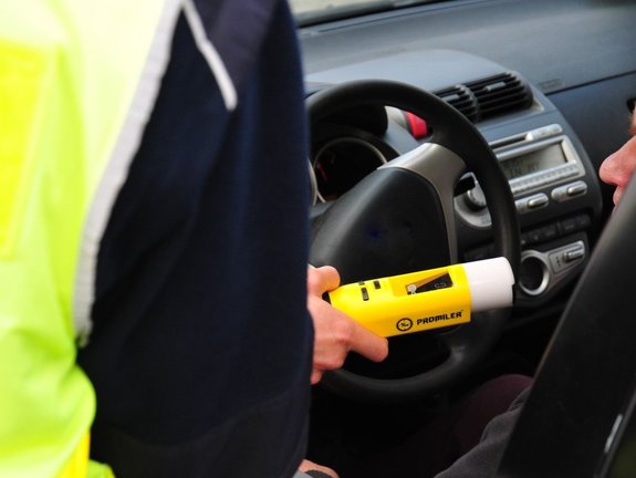 policjant podaje kierującemu urządzenie do sprawdzania stanu trzeźwości przez szybę pojazdu