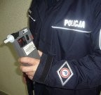 Umundurowany policjant trzymający w ręce urządzenie do badania trzeźwości.