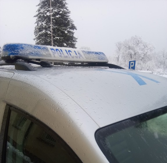 Oznakowany zaśnieżony radiowóz policyjny.