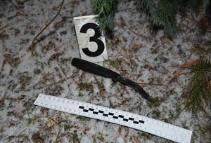 Na śniegu leży wygięty nóż. Obok niego skalówka oraz numer 3