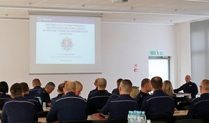Policjanci uczestniczący w naradzie. W tle wyświetlana prezentacja o treści informacja o stanie porządku i bezpieczeństwa publicznego w Krośnie i powiecie krośnieńskim w 2022 roku