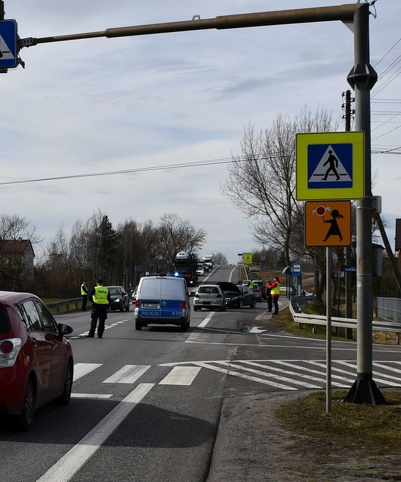 Na zdjęciu droga w miejscowości Trześń w gminie Gorzyce na której toyota yaris zderzyła się z oplem insignia.  na miejscu zdarzenia pracują umundurowani policjanci. W tle widoczny ruch pojazdów.