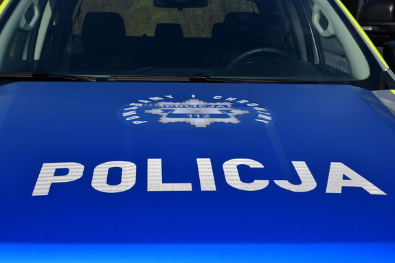 Maska radiowozu z białym napisem na niebieskim tle - POLICJA oraz policyjna gwiazda, którą okala napis - POMAGAMY I CHRONIMY