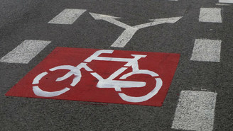 Na zdjęciu widoczna droga rowerowa na której widnieje rysunek roweru i dwóch strzałek informujących o kierunkach jazdy