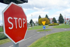 Na pierwszym palnie widoczny znak stop  a w dalszej perspektywie miasteczko ruchu drogowego
