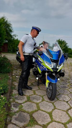 na motocyklu policyjnym siedzi dziecko, obok stoi umundurowany policjant