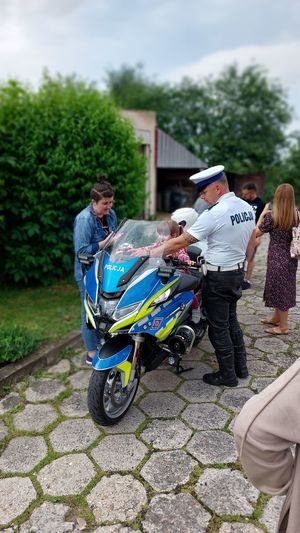 dziecko siedzi na motocyklu policyjnym, obok stoi policjant