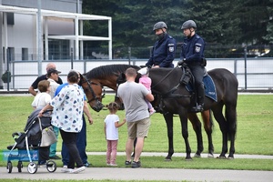 Dwaj policjanci na koniach oraz kilka osób stojąca obok
