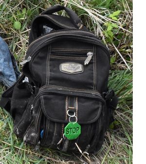 Na zdjęciu czarny plecak z zielonym odblaskiem z napisem stop.