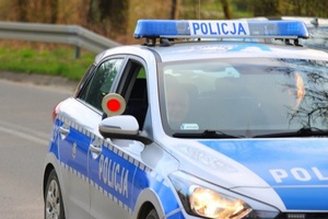 policjant siedzący w radiowozie z wyciągniętą tarczą do zatrzymywania pojazdów