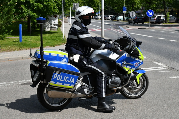 Policjant na motocyklu stoi na skrzyżowaniu.